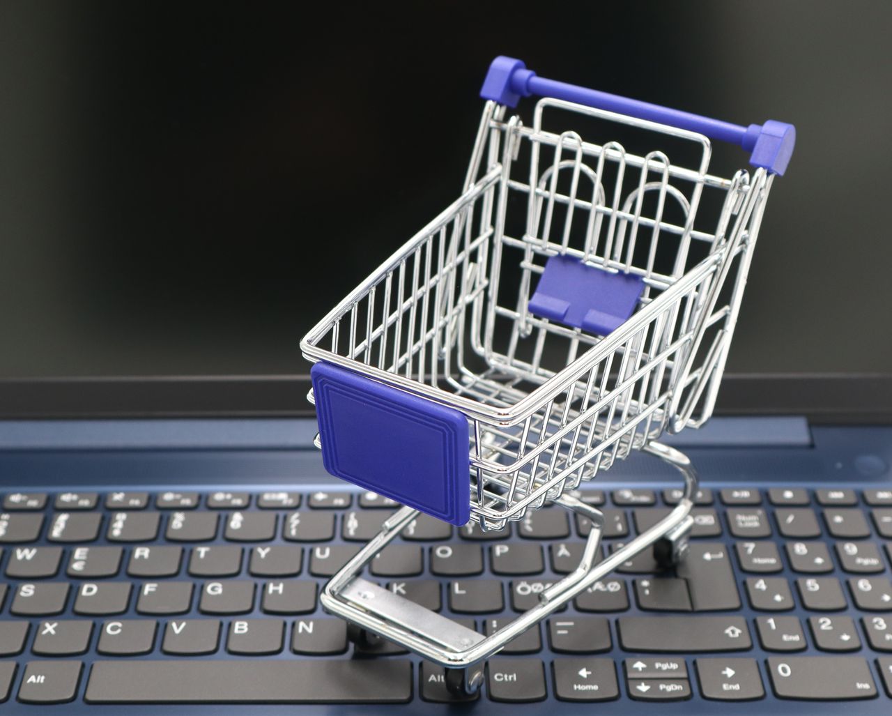 services-03 A mini shopping cart placed on a laptop keyboard, symbolizing online shopping and digital retail.